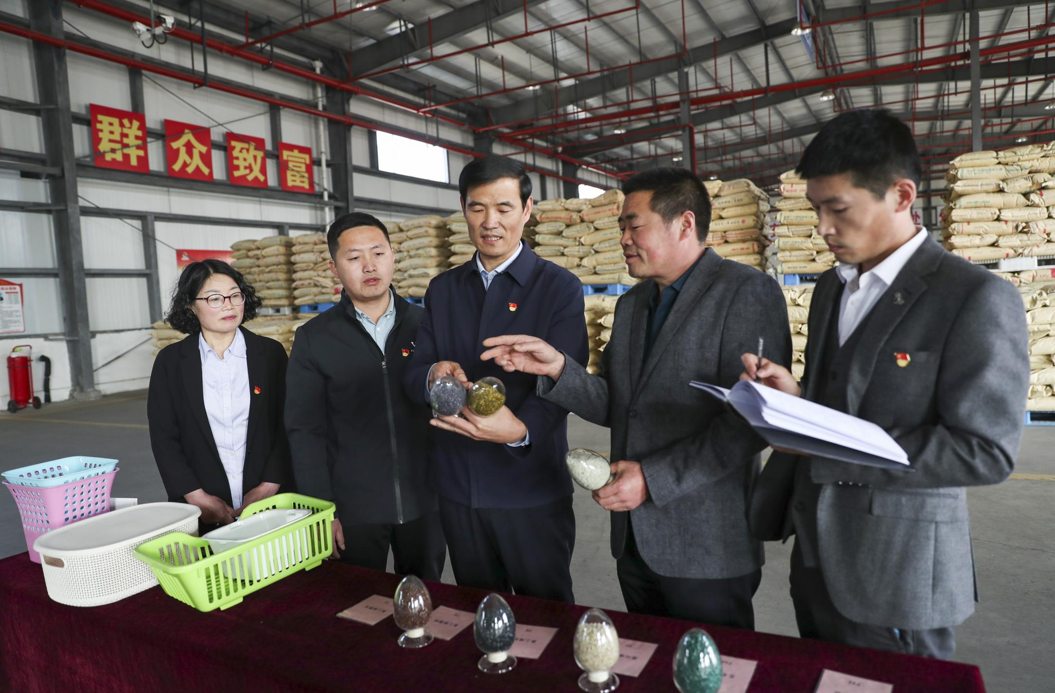 为加快实现尼龙颗粒加工产业升级，钟佰均从观念升级入手，带领党员干部外出参观学习，研究产业升级道路，规划产业发展方向。图为钟佰均带领党员干部研究新产品。.png